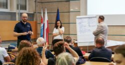 Spotkanie konsultacyjne ws. hałasu ulicznego w Urzędzie Miasta Gdyni — funkcjonariusz policji, moderatorka przy flipcharcie z postulatami mieszkańców i przedstawiciel urzędu, w tle uczestnicy spotkania